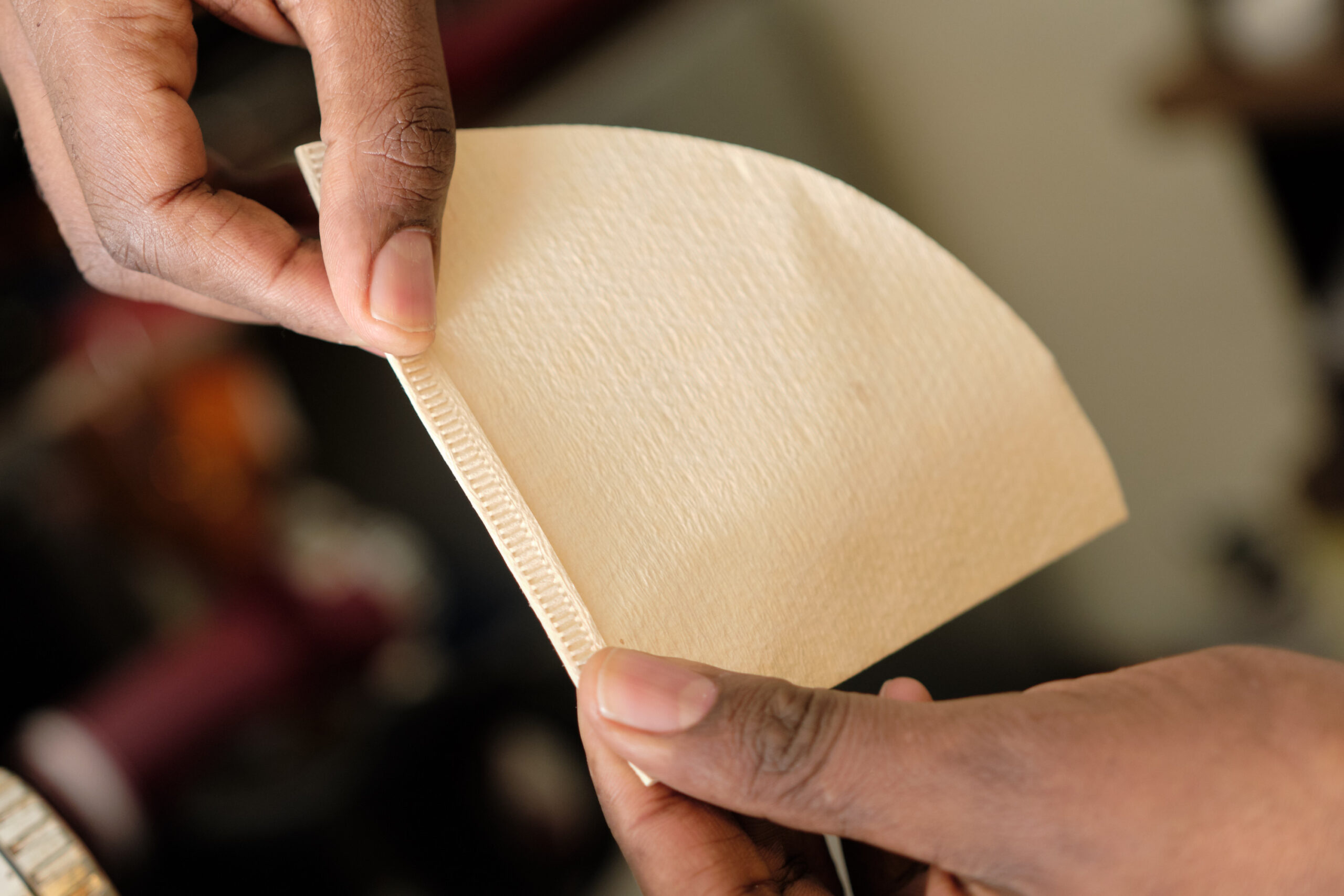 Hands holding an unbleached coffee filter